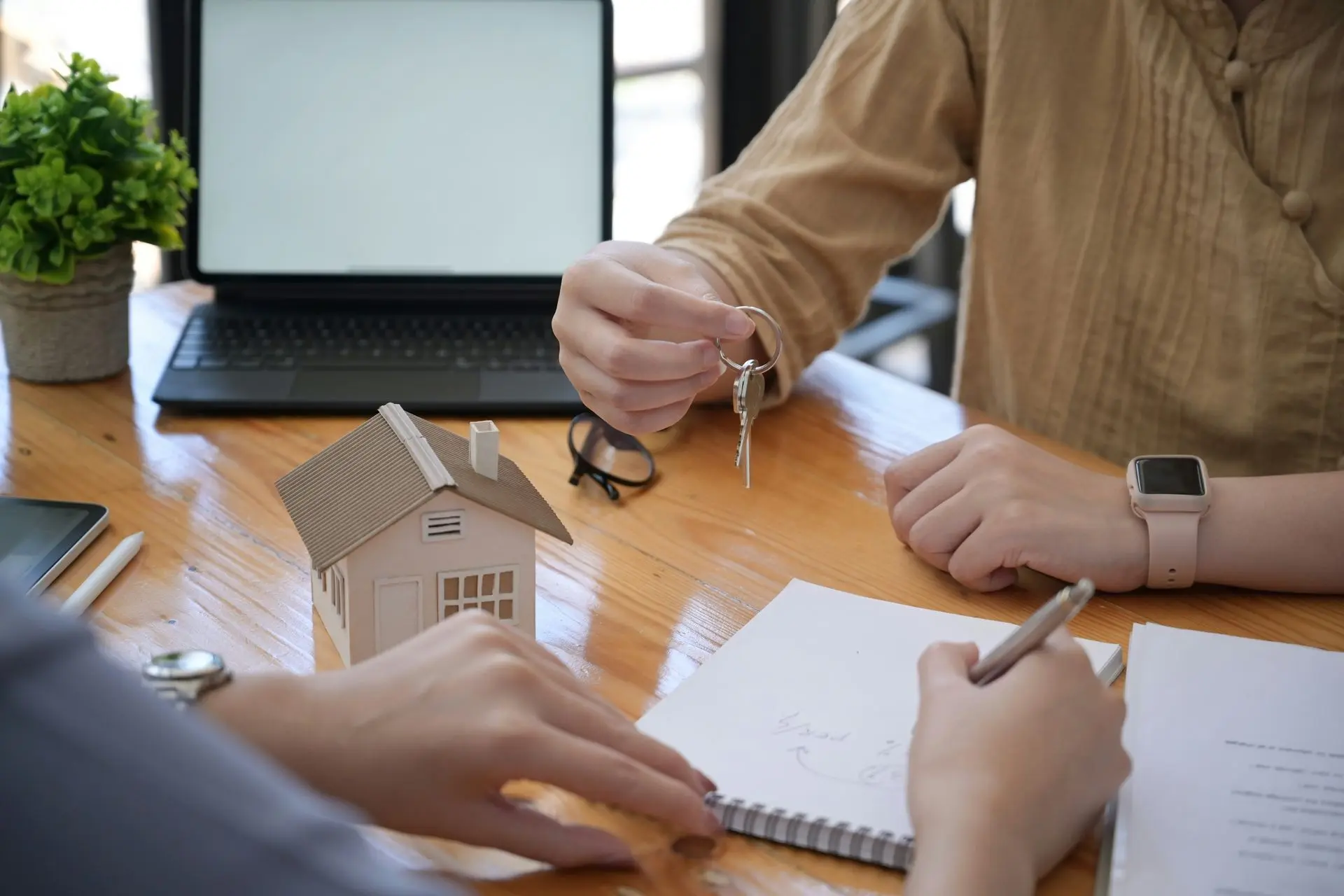 Vertragsunterzeichnung und Schlüsselübergabe beim Immobilienverkauf – persönliche und diskrete Abwicklung Schlüsselübergabe bei Immobilienverkauf mit Miniaturhaus und Vertragsunterlagen
