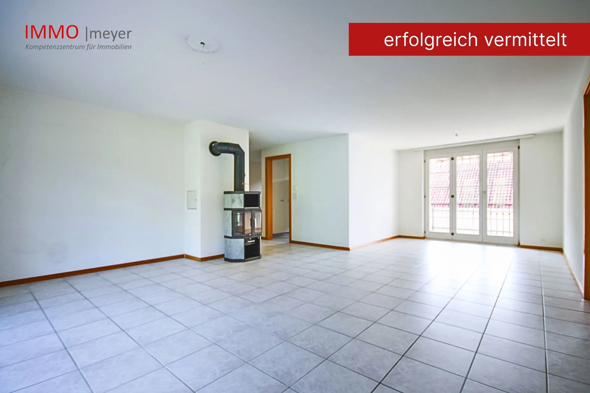 Geräumiges Wohnzimmer mit Kaminofen und Fensterfront