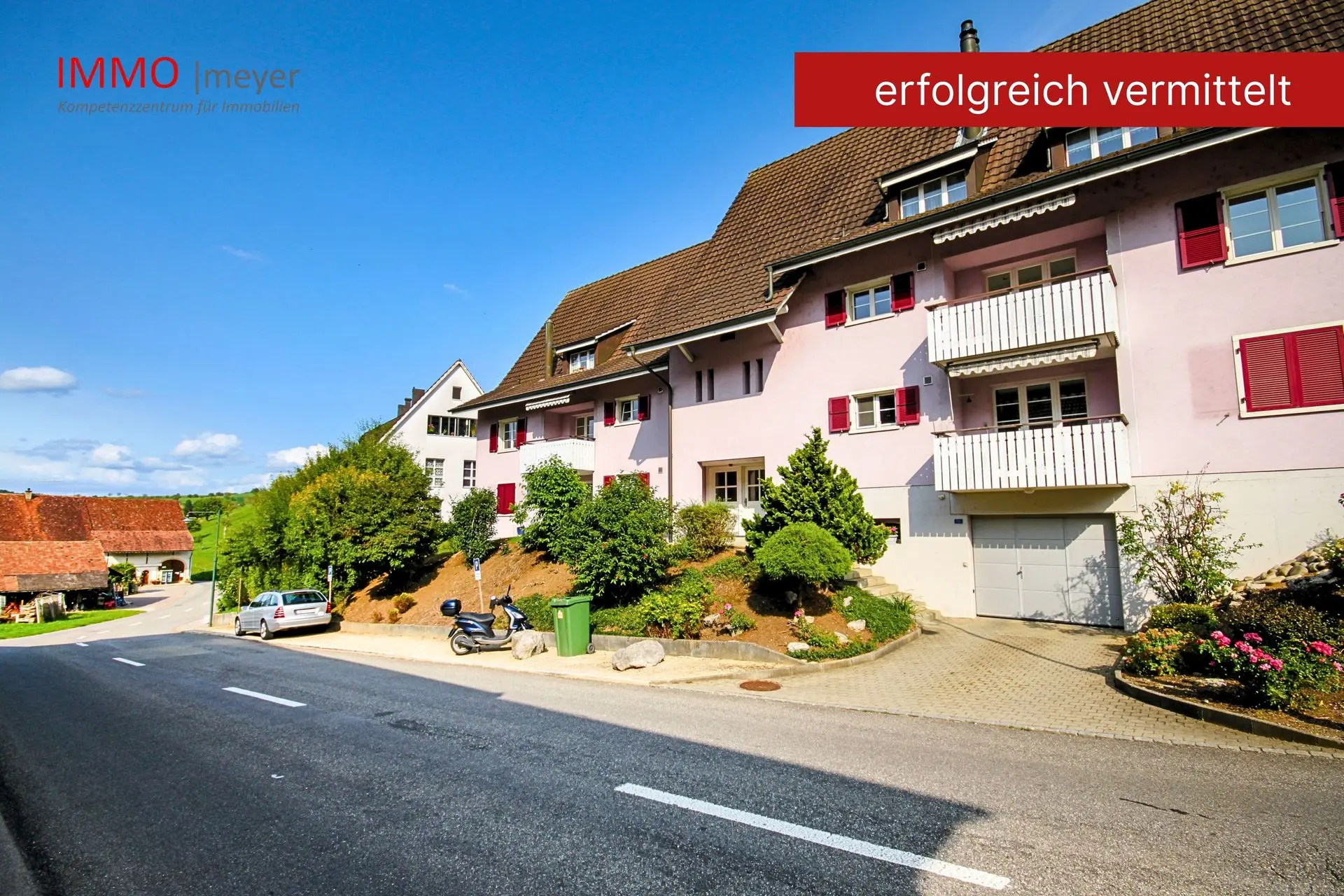 Mehrfamilienhaus mit Balkonen und bepflanztem Vorplatz