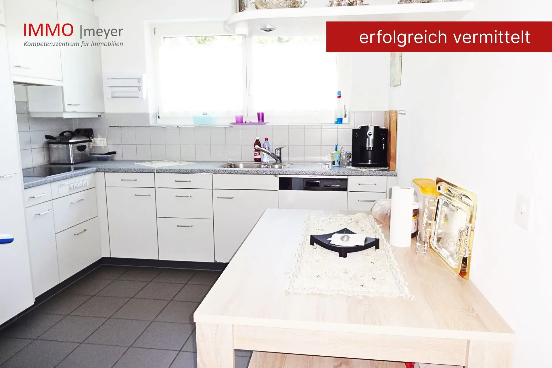 Küche mit weißen Schränken, Tisch und Fenster