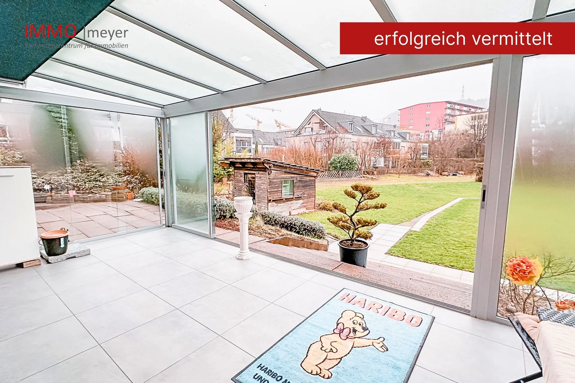 Glasveranda mit gefliestem Boden und Gartenzugang